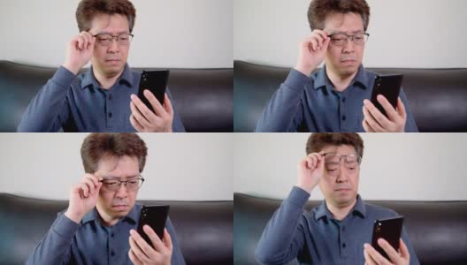 亚洲中年男性试图阅读他的手机。远视、近视。高清在线视频素材下载