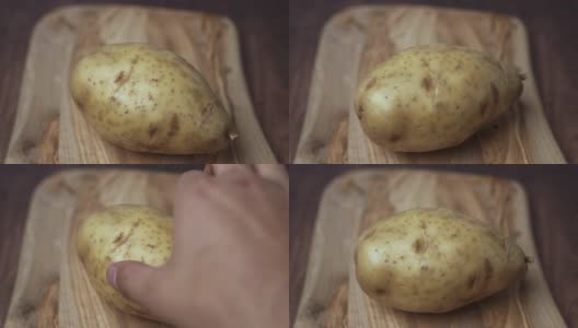 一个女人的手在一块木砧板上滚动着一个大土豆。b-roll风格的电影动作。高清在线视频素材下载