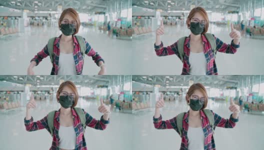 一幅亚洲妇女戴着口罩，竖起大拇指，邀请你在机场旅行的肖像高清在线视频素材下载