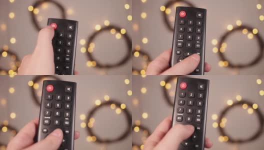 电视遥控器特写手指按下按键博克和圣诞灯在一个模糊的背景高清在线视频素材下载
