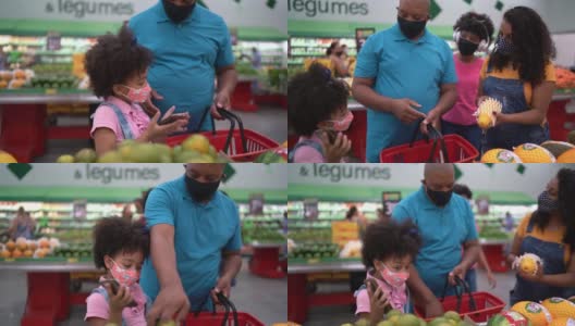 爸爸和女儿在超市用智能手机买水果——还戴着口罩高清在线视频素材下载
