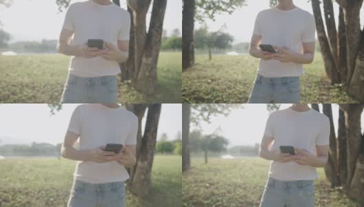 靠近一名身穿白衬衫的男性身体部位，在公园的树荫下散步，放松休闲活动，远程通讯设备，使用无线技术的手高清在线视频素材下载