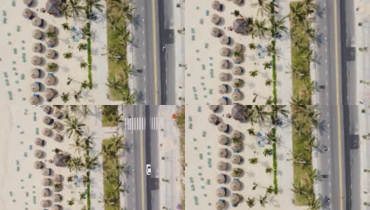 鸟瞰图的一个宏伟的白色沙滩与棕榈树，海滩小屋和道路与车辆的观点。高清在线视频素材下载