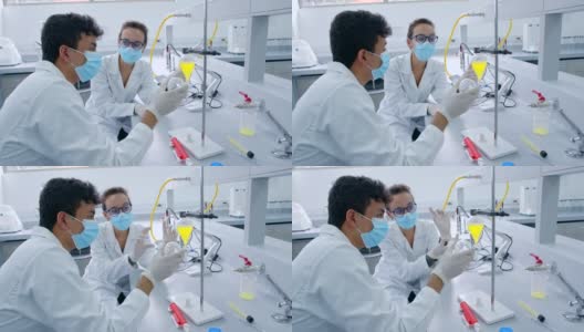 实验室的化学伙伴们戴着防护口罩和手套，一边讨论样品，一边等待反应高清在线视频素材下载