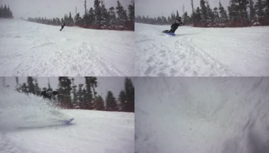 慢动作拍摄的滑雪板穿着完整的冬季齿轮雕刻在滑雪跑和喷涂雪在摄像机周围的埃尔多拉滑雪度假村附近的博尔德，科罗拉多州在一个下雪的，阴天，雪喷雾周围高清在线视频素材下载