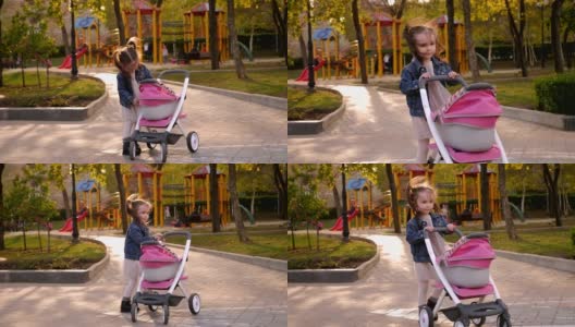 操场上的公园里，一个小女孩推着一辆婴儿车在她前面。高清在线视频素材下载