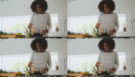 美丽的年轻混血女子微笑着在煎锅上做饭，在锅里翻蔬菜高清在线视频素材下载