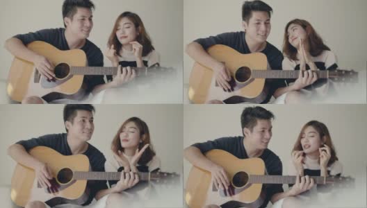 女孩唱歌，而她的男朋友在沙发上弹吉他。高清在线视频素材下载