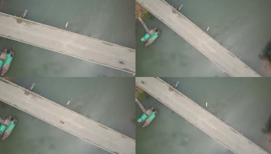 一名年轻女子骑着她的摩托车越过一座横跨热带河流的桥。高清在线视频素材下载