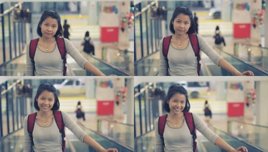 在自动扶梯上背着背包微笑的亚洲女士。健美的视频高清在线视频素材下载