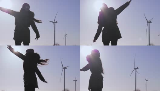 在阳光下旋转的风力发电站附近，一个黑色的女性身影高清在线视频素材下载