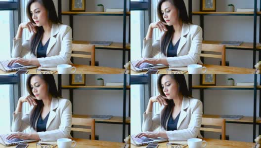 4K视频，忙碌的商务女性用笔记本电脑工作，严肃的思考在咖啡馆咖啡厅的早晨，商务人士的生活方式。30多岁的亚洲模特高清在线视频素材下载