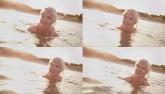 Active senior woman swimming in the sea at sunset高清在线视频素材下载