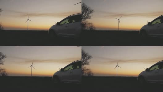 日落时风力发电站背景上的汽车高清在线视频素材下载