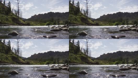 水沿着北福克肖肖尼河在科迪，怀俄明州与落基山脉在一个阳光明媚的日子背景慢动作拍摄高清在线视频素材下载
