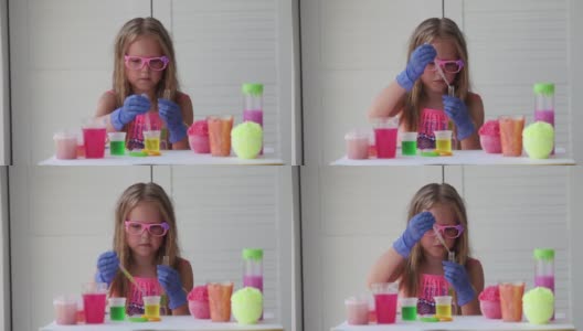 一个戴着粉色眼镜的小女孩做着实验，看着摄像机微笑着。一个戴着橡胶手套的孩子用吸管将一种黄色液体倒入试管中。实验。高清在线视频素材下载