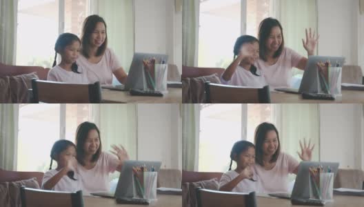 亚洲母女在家里的电脑上通过视频电话问候朋友。由于Covid - 19大流行，在隔离期间儿童在家上学，父母在家工作。高清在线视频素材下载