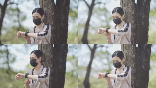亚洲年轻女性锻炼防护口罩和看运动手表高清在线视频素材下载