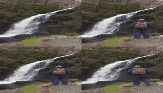 一个退休男子在春天的一天看瀑布高清在线视频素材下载
