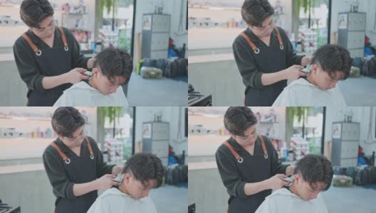 亚洲专业男性发型师用剪子为年轻男性顾客理发。年轻的美发师给一个男孩换发型。美容院，时尚或理发的经营理念高清在线视频素材下载