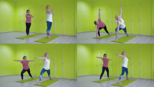 一个女孩和教练在大厅里练习瑜伽，做各种体式。高清在线视频素材下载