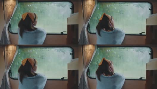 孤独的女人透过窗户看着雨。高清在线视频素材下载