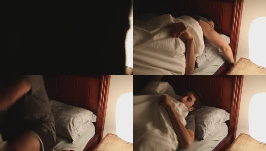 人准备睡觉时，从床头灯关上灯。年轻人躺在床上睡觉，给自己充电高清在线视频素材下载