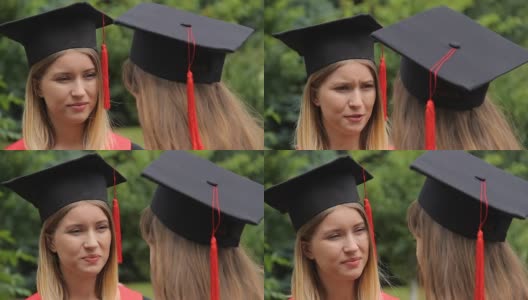 两个戴着带流苏的学术帽的年轻女子毕业后交流高清在线视频素材下载