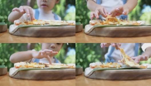 可爱饥饿的小女孩喜欢在后院吃自制的披萨。小女孩和家人在户外吃午饭。有选择性的重点。高清在线视频素材下载