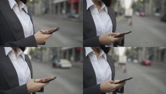 VDO慢动作。特写年轻的女商人在街上输入智能手机。女性的手打字智能手机。高清在线视频素材下载