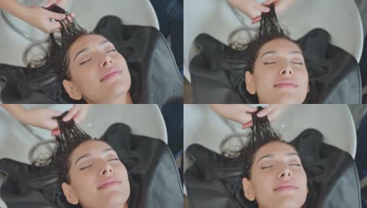 亚洲年轻女子躺下，闭上眼睛在沙龙洗床得到专业发型师洗头。美丽的顾客在美发厅或理发店享受美发师的按摩，心情舒畅高清在线视频素材下载