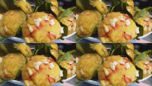 传统的蒸熟棕榈水果蛋糕，包裹着菠萝蜜叶子，撒上椰子片。近距离观察蒸棕榈饼。4 k的视频。高清在线视频素材下载