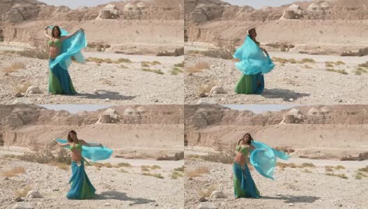 漂亮的女舞者。肚皮舞。沙漠。性感的绿蓝裙舞高清在线视频素材下载