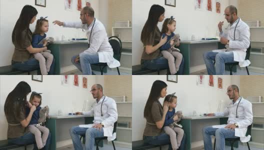 男儿科医生用手检查小女孩的头部温度，并给她温度计高清在线视频素材下载