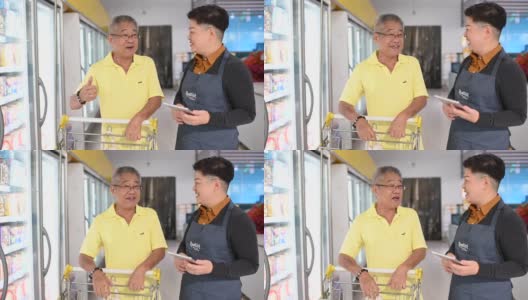 一位亚洲华人高级男子与一位穿着围裙的女店主交谈，询问店员的情况高清在线视频素材下载