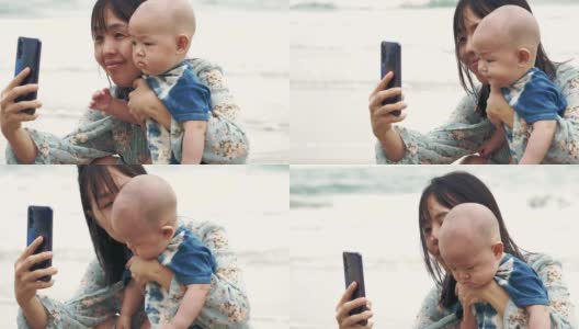 快乐的妈妈和小男孩用智能手机自拍高清在线视频素材下载