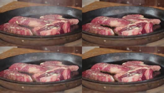 在铁锅里煎牛排。这家餐厅的专业厨师在家做饭。厨师把一块肉放在火上烤。煎烟。生肉蒸煮过程。高清在线视频素材下载