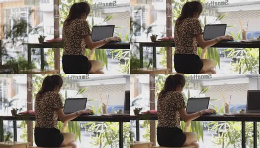 Panning:年轻的亚洲女性在咖啡馆用笔记本电脑工作高清在线视频素材下载