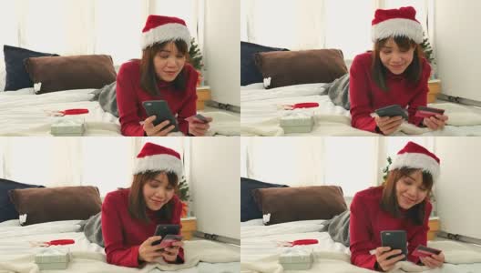 亚洲女人放松与她的智能手机和网上购物在圣诞节活动高清在线视频素材下载