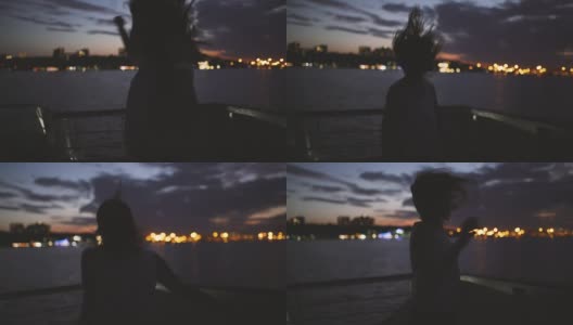 一个年轻快乐的女孩的剪影感觉可怕和舞蹈在船上在黑暗的夜晚高清在线视频素材下载