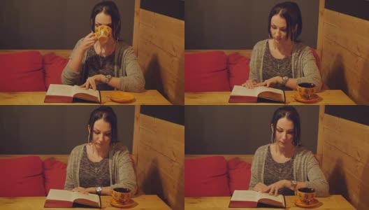 迷人的年轻女子坐在咖啡馆的沙发上看书和喝咖啡高清在线视频素材下载
