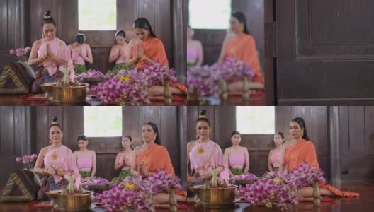 一群穿着泰国传统服装带着鲜花的泰国妇女呆在古老的房子里，向照相机表示敬意高清在线视频素材下载