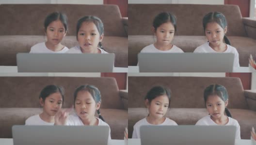 两名亚洲女童学生通过视频一起与老师在线学习。由于Covid - 19大流行，兄弟姐妹在隔离期间用电脑在家学习。高清在线视频素材下载