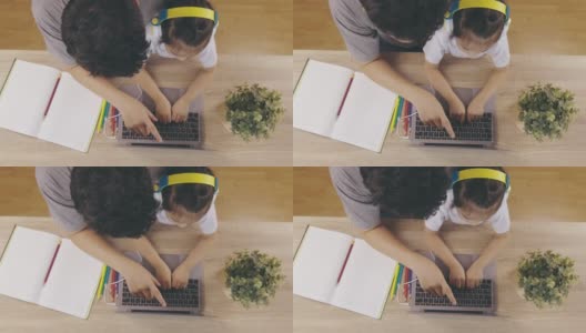 俯视图4K可爱的亚洲女孩的孩子，戴着耳机和手打字键盘，正在网上学习从电脑笔记本电脑与她的父亲教学显示父母支持教育在家里。高清在线视频素材下载