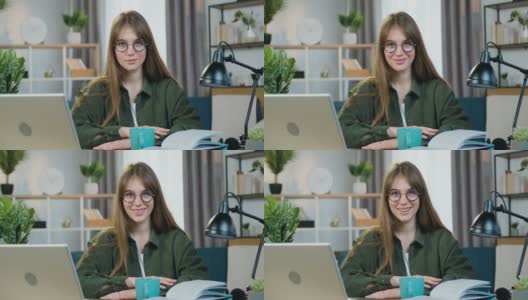 特写的漂亮快乐微笑无忧无虑时尚年轻女子在舒适的家庭办公室坐在相机前与自信的面部表情高清在线视频素材下载