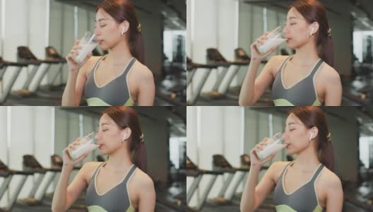 迷人的健身亚洲女性完成锻炼，并在训练后饮用蛋白质牛奶奶昔维生素。健身。健康的生活方式。高清在线视频素材下载