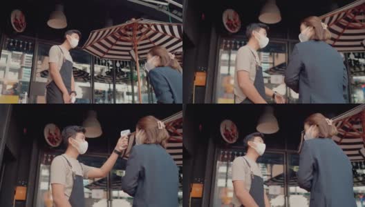 亚洲咖啡店的工作人员戴上外科口罩在店门口为顾客测温。高清在线视频素材下载