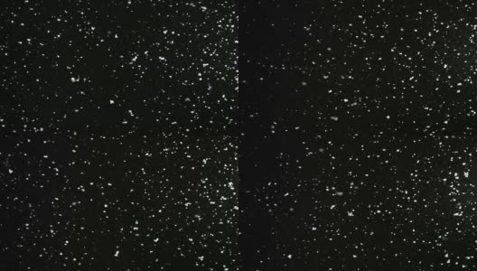 慢慢地飘落的蓬松的雪花孤立在黑色的背景，可循环。真实的镜头光晕，很容易使用混合/叠加模式。高清在线视频素材下载