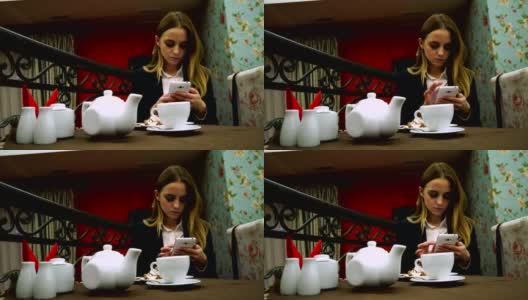 年轻女孩在咖啡馆边喝茶边用智能手机高清在线视频素材下载