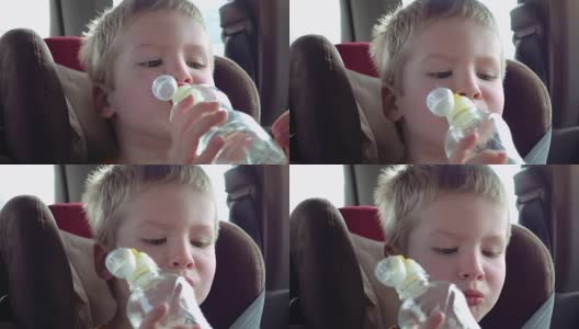 可爱的小男孩坐在儿童座椅上喝水高清在线视频素材下载